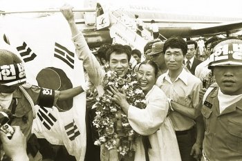 1974년 7월 남아공 더반에서 프로복싱 세계챔피언 타이틀을 딴 홍수환(꽃다발 건 사람)이 귀국 행사에서 어머니와 함께 기뻐하고 있다. 동아일보 자료 사진