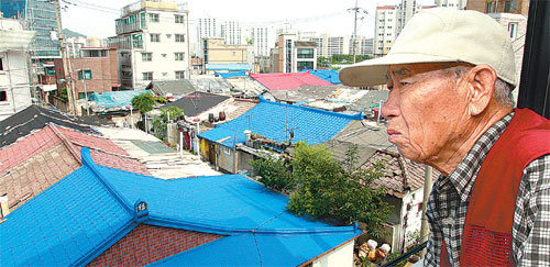 이희수 옹이 22일 반평생을 살아온 서울 마포구 상암동 반공포로주택촌을 바라보고 있다. 낮은 판자지붕 뒤로 디지털미디어시티(DMC)에 들어선 고층빌딩이 보인다. 홍진환 기자