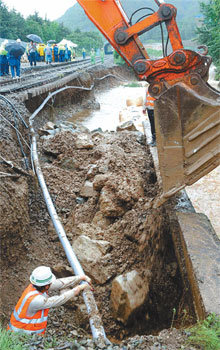 굴착기 동원해 철로 복구  16일 오전 집중호우로 유실된 경남 함안군 산인면 인근 경전선 철로를 인부들이 복구하고 있다. 한국철도공사(코레일)는 덤프트럭과 굴착기 등을 동원해 복구를 마쳐 이날 오후 6시 반경 열차 운행이 정상화됐다. 사진 제공 경남신문