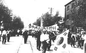 1960년 4월 태극기를 앞세운 시민들이 이승만 대통령의 하야를 요구하는 시위를 벌이고 있다.