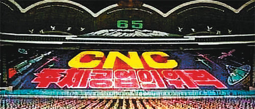 아리랑 공연도 김정은 업적 ‘CNC’ 선전 8월 2일 평양에서 열린 집체공연인 ‘아리랑’의 한 장면. ‘컴퓨터제어기술(CNC)’은 북한에서 김정은의 업적을 일컫는 상징으로 올해 처음으로 아리랑 공연에 등장했다.