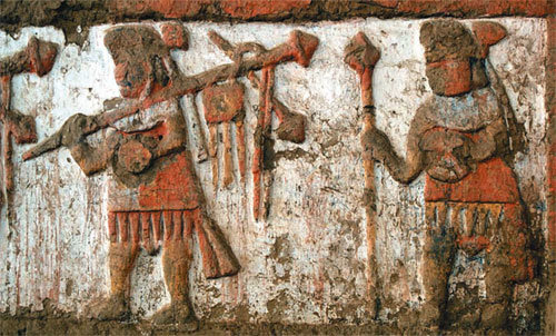 Relief of warriors on the walls of the moon temple or Huaca de la Luna. The warriors are carrying weapons in one hand and shields or the heads of enemies in the other.