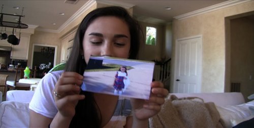 다니엘과 크리스티 부부의 딸 알리가 카메라로 셀프 동영상을 찍고 있다. 손에 들고 있는 것은 1편의 여주인공인 케이티의 어린 시절 사진.