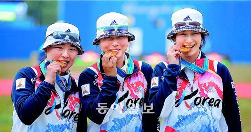 “그래! 이 맛이야.” 21일 아오티 양궁장에서 열린 광저우 아시아경기 양궁 여자단체 결승전에서 연장 접전 끝에 중국을 꺾고 아시아경기 4연패를 달성한 태극궁사들(왼쪽부터 윤옥희 주현정 기보배)이 시상식에서 금메달을 깨무는 포즈를 취하고 있다. 광저우=변영욱 기자 cut@donga.com