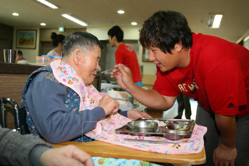 롯데 이대호(오른쪽)가 5일 부산 신망애요양원을 찾아 거동이 불편한 할아버지에게 밥을 먹여드리는 등 봉사활동을 펼치고 있다.