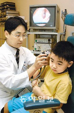 의사가 어린이 환자의 귀를 살피며 소아 난청의 원인인 중이염 감염 여부를 검사하고 있다.