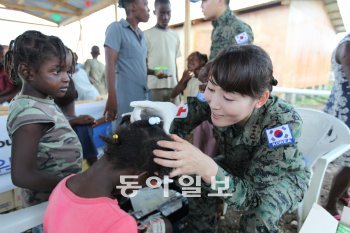 아이티에 파병된 한국군 ‘단비부대’의 김미화 대위가 아이티 어린이의 몸을 살피며 의료지원활동을 하고 있다. 사진 제공 단비부대