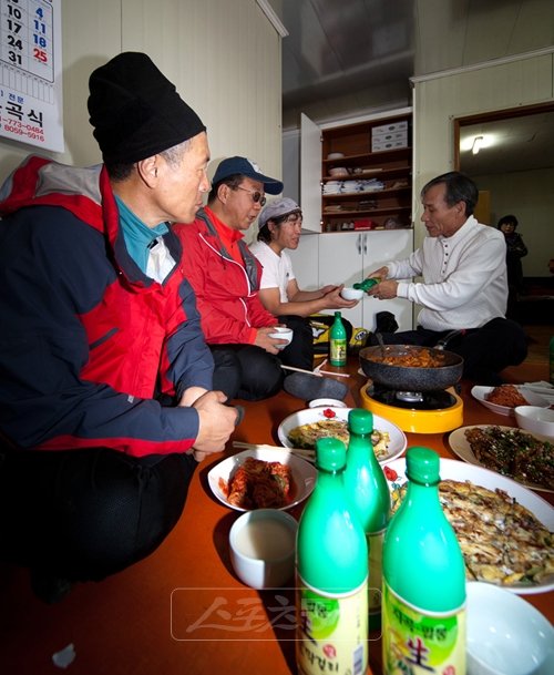캬! 몸도 마음도 사르르∼서산의 명물 지곡막걸리를 대를 이어 지켜가고있는 지곡양조장을 방문한 자전거식객팀. 양조장 발효실 앞에 마련된 툇마루에 돼지고기 두루치기, 망둥어, 갓김치, 빈대떡 등 주안상이 차려졌다. 오른쪽 끝(흰색 상의)이 양조장 사장 하광철씨다.