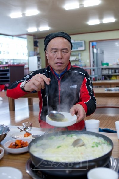 비포장도로를 찾다 구매항 부근 야산과 갯바위를 헤맨 탓에 오후 3시가 다 되어서야 식당을 만나 점심식사를 할 수 있었다. 미각을 찾는 여행은 장마다 꼴뚜기는 아니지만 때로 전혀 기대하지 않은 곳에서 뜻밖의 별미를 만나기도 한다. 안면도 77번지방도 장곡리 부근에서 추위에 쫓겨 무작정 들어간 식당(중앙가든)의 살조개 칼국수가 그러했다. 대장 허영만 화백이 대원들에게 칼국수를 떠주고 있다.