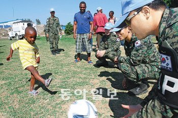 아이티에 파병돼 지진피해 복구와 구호활동을 수행하고 있는 단비부대 장병들이 지난달 28일 보육원을 찾아 축구공 기증 행사를 연 뒤 한 어린이가 공을 차는 모습을 보고 있다. 합참 제공