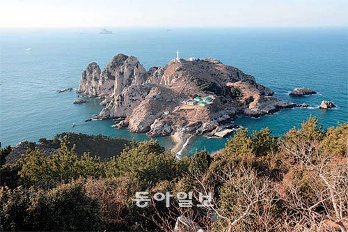 매물도 등대섬이 3월의 아침햇살 아래서 환희 빛나고 있다. 섬 중턱에 항로표지관리소 관사가 보이고 그 아래로 썰물때만 드러나는 자갈톱이 보인다. 소매물도의 망태봉(해발 152m)에서 촬영.