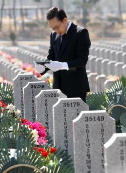 이명박 대통령이 26일 대전 유성구 국립대전현충원에서 열린 천안함 용사 1주기 추모식에 앞서 46용사 묘역을 둘러보며 한 용사의 가족사진을 바라보고 있다. 연합뉴스