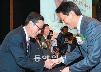 김윤철 관악문화원 원장(왼쪽)이 형편이 어려운 노인과 청소년을 31년간 도운 공로로 6일 오세훈 서울시장에게서 국민훈장 동백장을 받고 있다. 김범석 기자 bsism@donga.com