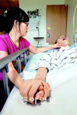 “일어나, 동은아” 오동은 병장은 군 의료진이 결핵을 우울증으로 오진하는 바람에 뇌막염으로 악화돼 의식불명에 빠졌다. 어머니 정영숙 씨가 12일 경기 부천시 원미구 부천순천향병원 입원실에서 아들의 손을 붙잡고 안타깝게 쳐다보고 있다. 부천=변영욱 기자 cut@donga.com