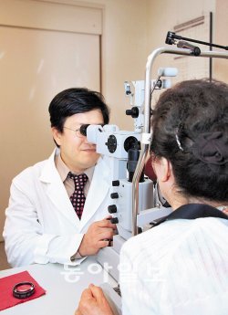 유형곤 서울대병원 안과 교수(왼쪽)가 망막 검사기기로 황반변성 여부를 검사하고 있다. 황반변성 망막질환은 망막의 중심 부위에 이상이 생기는 질환. 망막에서 비정상적인 신생 혈관이 나타나면 이 질환을 의심할 수 있다. 서울대병원 제공