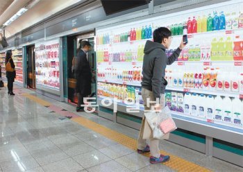 제일기획이 지난해 11월 서울 지하철 한강진역 승강장 안전문(스크린도어)에 설치한 ‘홈플러스 전철역 가상 매장’ 광고. 한 소비자가 스마트폰으로 음료 가격표에 붙은 QR코드를 이용해 모바일 쇼핑을 하고 있다. 제일기획 제공