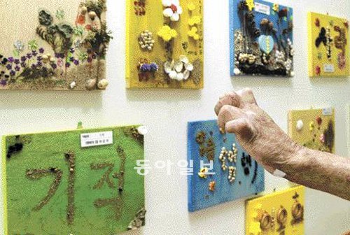 손은 오그라들고 뭉그러졌지만 그 손에서는 소박함을 담은 아름다움이 가득 우러나왔다. ‘소록도-행복한 웃음으로 피어나다’전의 개막식이 열린 19일 전남 고흥군 국립 소록도병원에서 한센병 환자 한 사람이 손을 들어 자신과 이웃들이 출품한 작품들을 가리켜 보이고 있다. 소록도=서영수 전문기자 kuki@donga.com