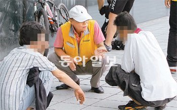 20일 오후 서울역 입구에 모여 있는 노숙인들과 현장 상담을 하고 있는 다시서기지원센터 상담사 노경준 씨(가운데). 한국철도공사(코레일)는 최근 서울역 안에 노숙인이 머무르지 못하게 하는 조치를 취했다. 원대연 기자 yeon72@donga.com