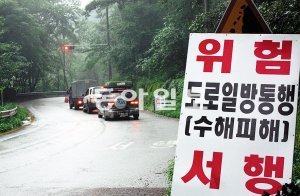 1개 차로만 통행 강원 춘천시 신북읍 소양강댐 진입도로가 지난달 말 집중호우로 인한 산사태로 도로 일부가 훼손돼 부분통제되고 있다. 이인모 기자 imlee@donga.com