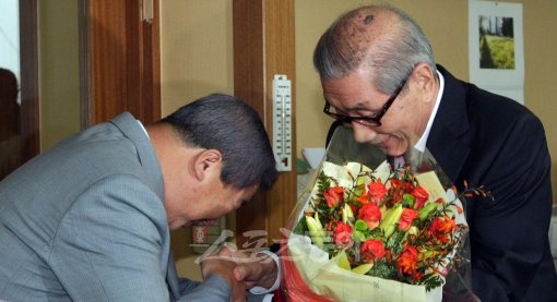 KBO 구본능 신임 총재(왼쪽)가 22일 취임식에서 자신이 받은 축하 꽃다발을 다시 이용일 총재대행에게 전하며 그간의 노고에 고마워하고 있다.