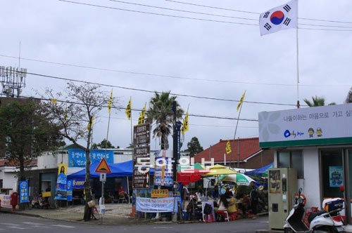 제주해군기지 반대단체 측이 중덕삼거리에서 강정마을 사거리까지 200∼300m 거리에 무허가 시설물을 설치하고 올레코스 탐방객 등을 상대로 음료수를 팔고 있다. 오른쪽 건물은 해군기지 찬성 측 주민이 운영하는 편의점으로 골목을 사이에 두고 있다. 서귀포=임재영 기자 jy788@donga.com