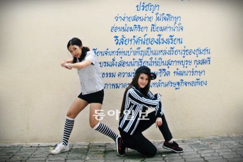 방콕에서 가장 유명한 케이팝 댄서인 보보(Bowbo·왼쪽)가 데뷔를 준비중인 연습생과 함께 태국어 간판 앞에서 포즈를 취했다. 그녀가 가장 좋아하는 가수는 2NE1의 \'CL\'이라고 말한다. 정호재 기자 demian@donga.com　　
