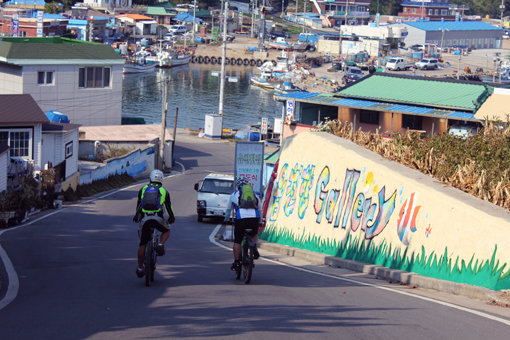 각양각색의 벽회들로 마을 전체가 갤러리인 읍천항 마을길로 진입하고 있는 자전거일주팀. 민가의 담벼락, 대문은 물론 방파제나 도로바닥에도 예술의 향기가 물씬 풍기는 그림이 즐비해 여행객들의 눈길을 사로잡는 마을이다.