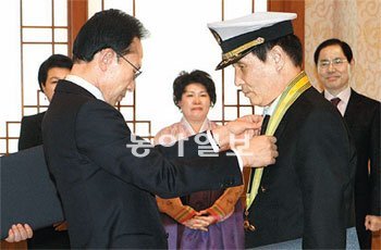 “수고하셨습니다” 이명박 대통령은 31일 청와대에서 올 1월 소말리아 해상에서 해적들에게 총상을 입은 뒤 기적적으로 살아난 석해균 당시 삼호주얼리호 선장(오른쪽)에게 국민훈장 동백장을 수여했다. 부인 최진희 씨가 한복 차림으로 지켜보고 있다. 청와대사진기자단