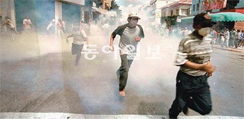 2000년 4월, 볼리비아 제3의 도시 코차밤바에서 수돗물값 인상에 항의하던 시위자들이 경찰이 쏜 최루탄을 피해 달아나고 있다. 동아일보DB