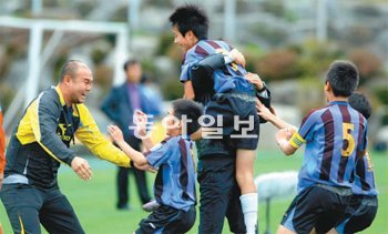 김해외동초교 안재현(위)이 6일 대교눈높이컵 초등축구리그 왕중왕전 결승에서 후반 9분 선제골을 터뜨린 뒤 코치진과 얼싸안고 기쁨을 나누고 있다. 원대연 기자 yeon72@donga.com