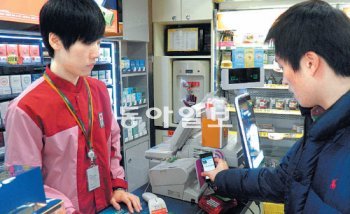 24일 서울 중구 명동 입구의 한 편의점에 들어가 스마트폰의 근거리무선통신(NFC) 기능을 활용해 입술보호제와 메모용 포스트잇값을 결제했다. 일반 신용카드로 물건을 살 때와 똑같아서 편리하다.