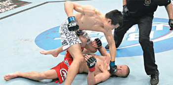 소나기 파운딩 ‘코리안 좀비’ 정찬성(왼쪽 위)이 11일 캐나다 토론토의 에어캐나다센터에서 열린 UFC
 140대회 페더급 경기에서 1라운드가 시작되자마자 오른손 강펀치를 날려 쓰러뜨린 마크 호미닉(캐나다)의 얼굴에 소나기 펀치를 
퍼붓고 있다. UFC 홈페이지