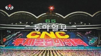 전문가들은 북한이 김정은의 치적으로 내세운 CNC(컴퓨터제어기술)를 중심으로 첨단화, 과학화, 세계화란 슬로건을 채택할 것이란 전망을 내놓고 있다. 사진은 지난해 8월 2일 평양에서 열린 집단체조 아리랑 공연에서 등장한 ‘CNC 주체공업의 위력’이란 구호. 동아일보DB