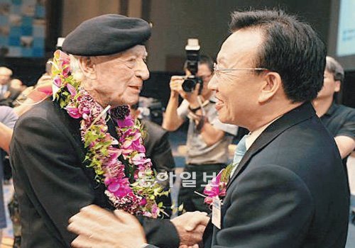 김관용 경북도지사(오른쪽)가 지난해 대구에서 열린 낙동강 전투 참전용사 세미나에서 전투 증언을 한 영국인 참전용사에게 꽃다발을 걸어주며 격려하고 있다. 경북도 제공