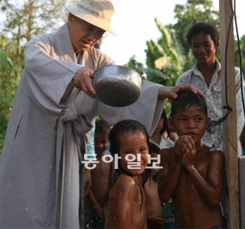 송월주 스님이 2010년 1월 캄보디아 캄포트주의 한 마을에서 진행된 ‘생명의 우물’ 1000기 완공 기념식에서 아이들에게 물을 부어주고 있다. 경기 오산시에 거주하는 송명례 할머니가 후원했다. 지구촌공생회 제공
