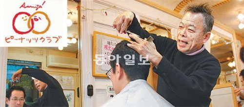 “피너츠 덕에 힘 납니다” 일흔의 나이에도 불구하고 일본 지바 시 유리노키 거리에서 현역 이발사로 활동하고 있는 가이호 마코토 씨가 자신의 이발관에서 고객의 머리를 다듬고 있다. 피너츠 로고(왼쪽 위 작은 사진)는 스페인어로 ‘친구’를 의미하는 ‘아미고’가 쓰여 있어 지역 민간 유대와 교류를 중시하는 지역 화폐의 의미를 강조하고 있다.