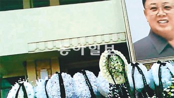 김일성 사적관의 ‘향기없는 弔花’ 지난해 12월 17일 북한 김정일 국방위원장이 사망한 후 함경북도 나선시의 ‘김일성 사적관’ 에 마련된 김 위원장의 분향소 앞에 화환이 놓여 있다. 이 중 대부분은 생화를 구하지 못해 종이와 헝겊으로 만든 것이다. 사적관 건물에는 멀리 정문 입구에서도 보일 정도로 큰 김 위원장의 사진이 걸렸다. 나선=동아일보 통신원 A 씨