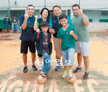 브라질 상파울루 주 이타페바 시 외곽 산타마리아 마을에 있는 우경호 씨의 어린이개발센터 내 축구장에서 에우시우(24), 우경호 씨와 부인 강순옥 씨(49), 니콜라스(25), 조나탄(10), 그레고리(10·이상 뒷줄 오른쪽부터 시계 반대 방향)가 함께했다. 약물과 범죄의 고리를 끊은 에우시우와 니콜라스는 각각 교사와 선교사가, 조나탄과 그레고리는 네이마르 다 시우바 같은 축구선수가 되고 싶다고 했다. 기아대책 제공