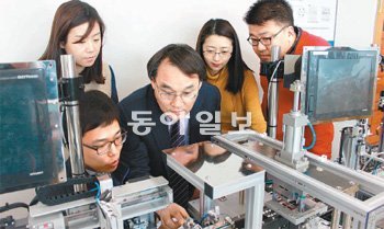 한국기술교육대 산학협력단 진경복 단장(가운데)이 직원들과 함께 새로 도입한 교육용 자재인 LED공정제어장비를 점검하고 있다. 천안=이기진 기자 doyoce@donga.com