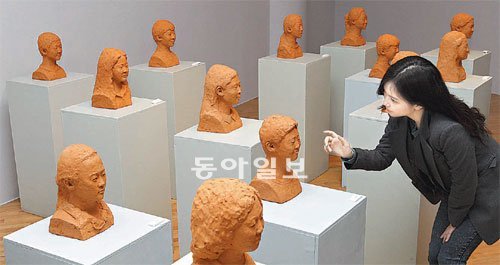 분원초등학교 안준철 교장이 만든 졸업생 얼굴상 22점이 서울 종로구 소격동 아트선재센터에 전시돼 있다. 관람객이 흥미롭게 얼굴상을 살펴보고 있다. 홍진환 기자 jean@donga.com