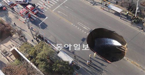 도로 한복판 27m 깊이 구멍 ‘뻥’ 지반이 침하돼 도로가 27m 아래로 꺼지는 사고가 난 인천 서구 왕길동 도로가 포탄에 맞은 듯 뻥 뚫려 있다. 19일 인천지하철 2호선 공사장 지반이 무너져 일어난 사고로 오토바이를 타고 가던 음식점 배달원 1명이 매몰돼 숨졌다. 인천서부소방서 제공