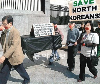 “탈북자들을 구해주세요” 1일 미국 워싱턴 중국대사관 앞에서 탈북자 강제 북송 반대 시위대가 북송되는 탈북자의 운명을 상징하는 ‘죽음의 관’을 들고 행진하고 있다. 워싱턴=정미경 특파원 mickey@donga.com