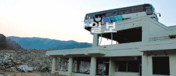 버스 언제나 내려올까 일본 미야기 현 이시노마키 오가쓰마을 공민회관 옥상에 얹혀진 버스. 회관 옆에 산을 이루고 있는 잔해물 더미와 함께 지난해 처참했던 쓰나미의 악몽을 떠오르게 한다. 이 버스는 10일 철거될 예정이다.