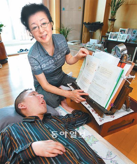 ‘연세대 스티븐 호킹’ 신형진 씨가 지난해 9월 서울 강남구 자택에서 어머니 이원옥 씨의 도움을 받아 책을 보는 모습. 이 씨는 “아들을 정성껏 보살펴 준 학교에 고맙다”며 2008년부터 이달 5일까지 총 2억 원을 기부했다. 최혁중 기자 sajinman@donga.com