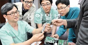 경북대병원 모발이식센터 김문규 교수(왼쪽)가 전자업체 연구원들과 함께 개발하고 있는 자동식모기의 성능을 살펴보고 있다.
