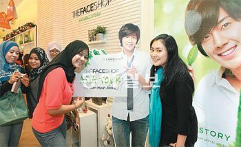 더페이스샵 말레이시아 매장에서 현지 고객들이 더페이스샵 모델 김현중의 아시아 투어를 기념해 만든 사진판 앞에서 촬영을 하고 있다. LG생활건강 제공