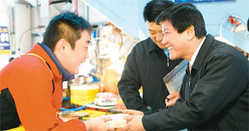 조준희 IBK기업은행장(오른쪽)은 일회성 영업활동을 없애는 등 기발한 아이디어로 혁신을 이끌고 있다. 조 행장이 지난해 4월 부산 자갈치 시장을 찾아 상인들에게 기념품을 나눠주는 모습. IBK기업은행 제공