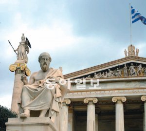 그리스 아테네 중심에 설립된 아카데미아의 건물 앞에 플라톤의 조각상이 근엄한 표정으로 시민들을 내려다보고 있다. 왼쪽 뒤의 입상은 아테네 시 이름의 유래가 된 지혜와 전쟁의 여신 ‘아테나’. 오른쪽 아카데미아 건물 중앙에 그리스 국기가 게양되어 있다. 아테네=구자룡 기자 bonhong@donga.com