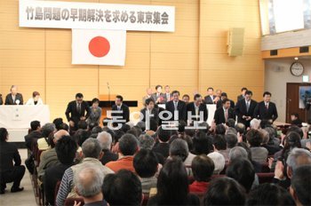 망언 쏟아내는 日 의원들 일본 도쿄 헌정기념관에서 11일 열린 ‘독도는 일본땅’이라고 주장하는 집회에 참석한 여야 국회의원들이 자리에서 일어나 참가자들에게 인사하고 있다. 도쿄=배극인 특파원 bae2150@donga.com