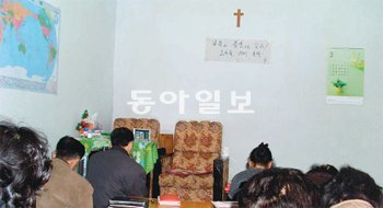 북한과 중국 접경지역에 있는 한 교회에서 신도들이 기도를 하고 있다. 벽에 걸린 십자가 밑에 ‘복음의 증인으로 살자. 조국을 위해 울라’라는 글이 적혀 있다. 북-중 접경지역=고기정 특파원 koh@donga.com